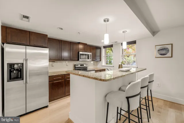a kitchen with stainless steel appliances granite countertop a sink and a refrigerator