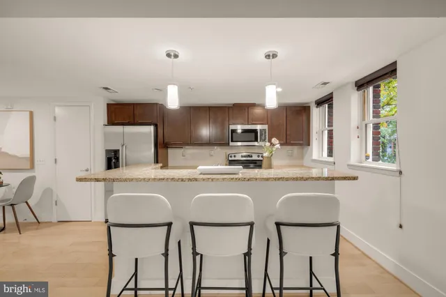 a kitchen with kitchen island granite countertop wooden cabinets and white appliances