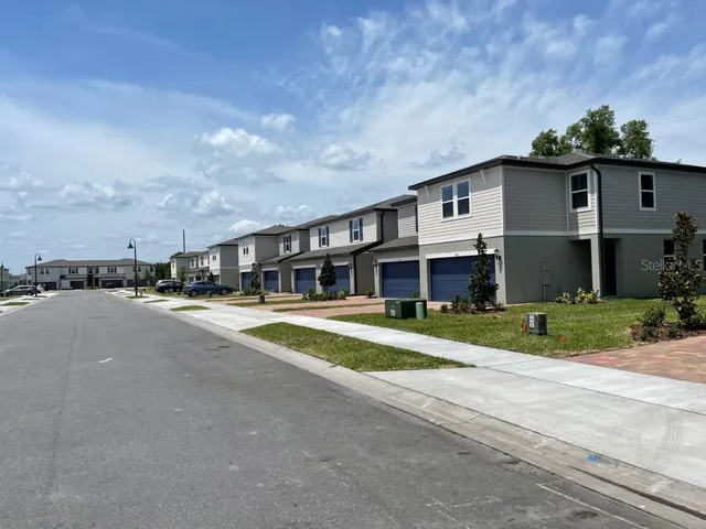 a view of a white house with a big yard and potted plants