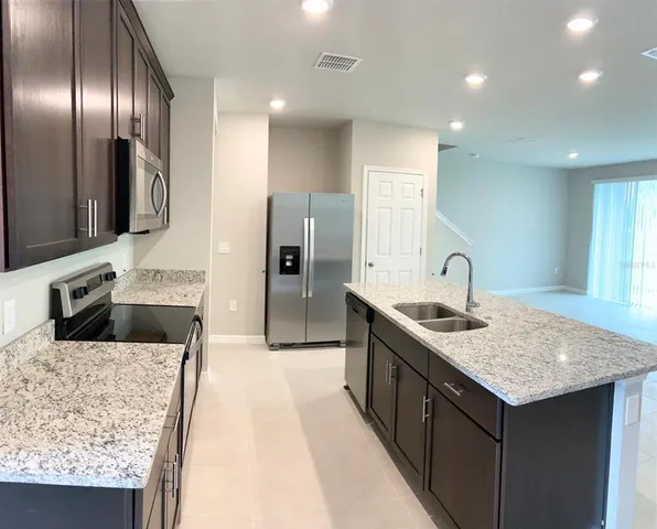 a kitchen with granite countertop stainless steel appliances a sink stove and refrigerator