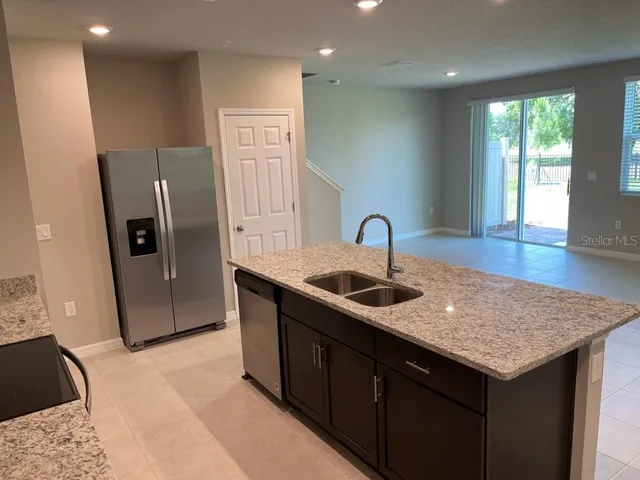 a kitchen with stainless steel appliances granite countertop a sink and a refrigerator