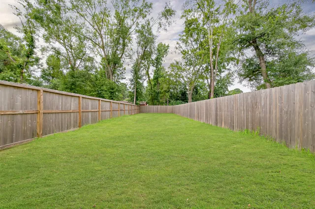 a view of a backyard with a fence and trees