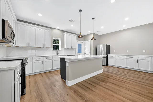 a large kitchen with stainless steel appliances sink a microwave and cabinets