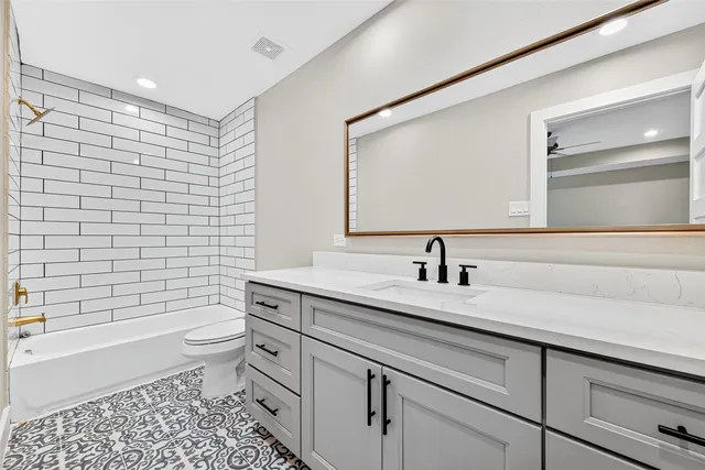 a bathroom with a granite countertop toilet a sink a mirror and shower