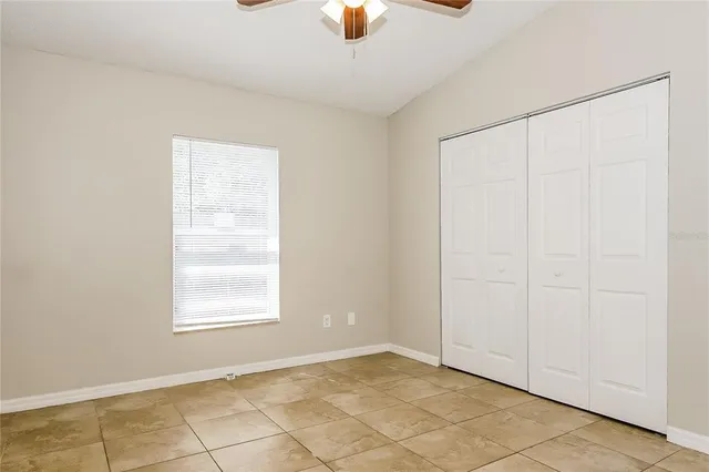 an empty room with windows and chandelier fan