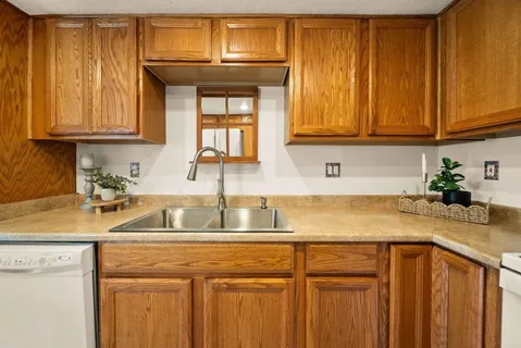 a kitchen with granite countertop a sink stainless steel appliances cabinets and a window