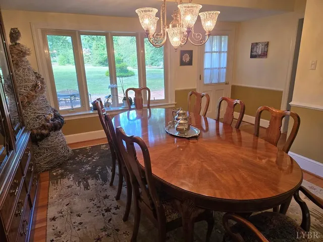 a view of a dining room with furniture a chandelier and large windows