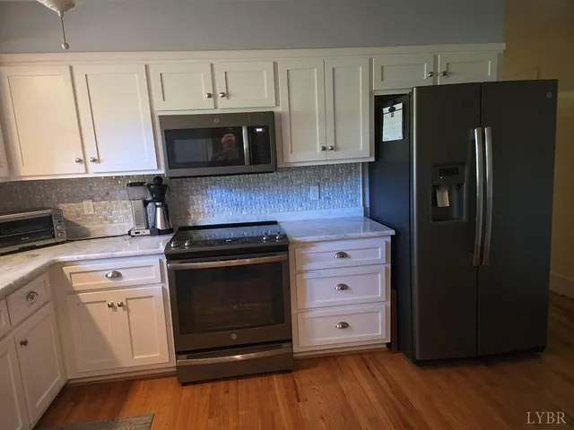 a kitchen with granite countertop white cabinets and stainless steel appliances