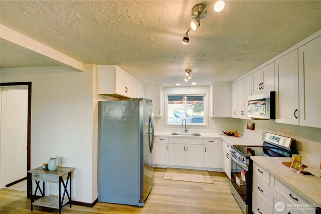 a kitchen with granite countertop a sink a stove and cabinets