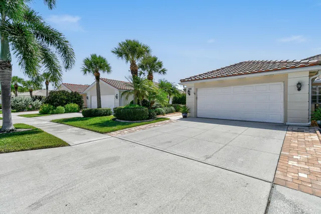 front view of a house with a yard and palm trees