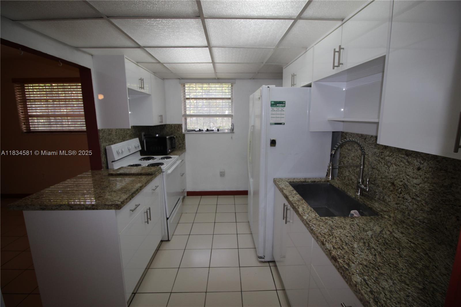 2216 Southwest 62nd Avenue Miami, FL 33155 - Photo 3 of 14 a kitchen with granite countertop a sink a stove and cabinets