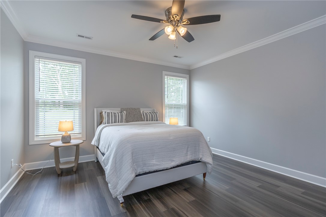 3080 McGee Road Iva, SC 29655 - Photo 29 of 49 Tasteful crown molding enhances this comfortable bedroom with modern plank flooring and ample natural light.