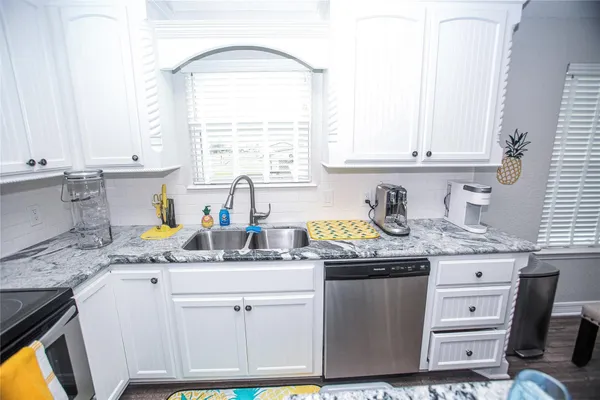 a kitchen with stainless steel appliances granite countertop a sink a stove a counter space and cabinets