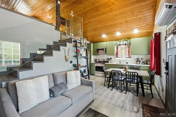 a kitchen with stainless steel appliances granite countertop a stove a refrigerator a sink dishwasher and a dining table with wooden floor