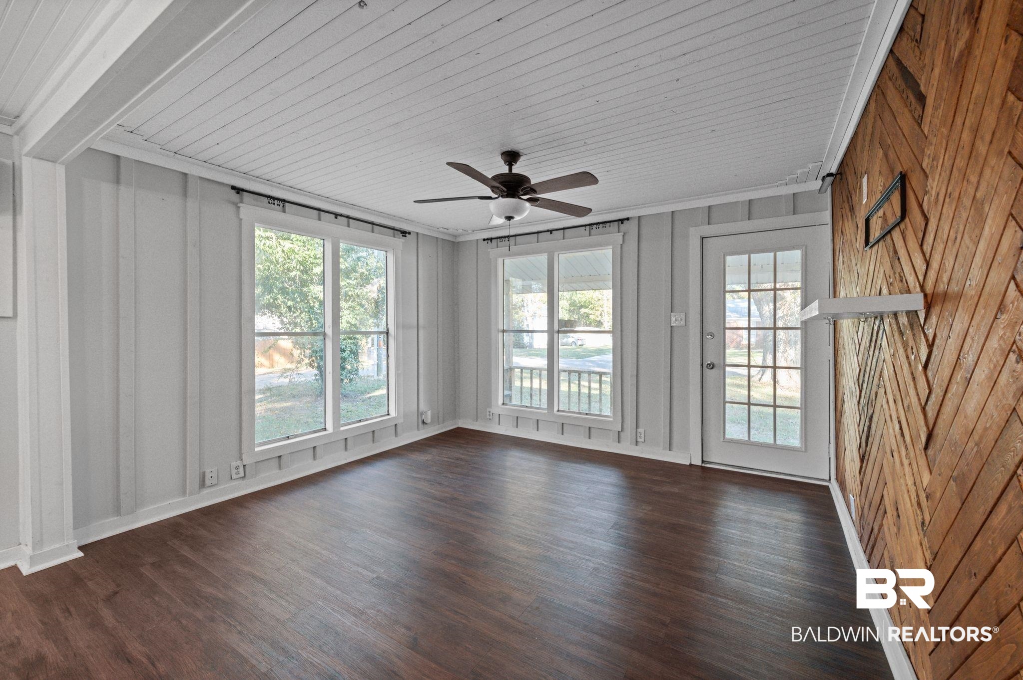 503 North Holly Street Foley, AL 36535 - Photo 7 of 23 Empty room featuring wood walls, ornamental molding, dark wood-type flooring, and ceiling fan