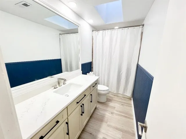 a bathroom with a sink a toilet a mirror and shower