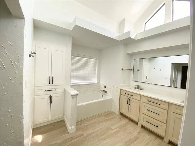 a spacious bathroom with a tub sink and mirror