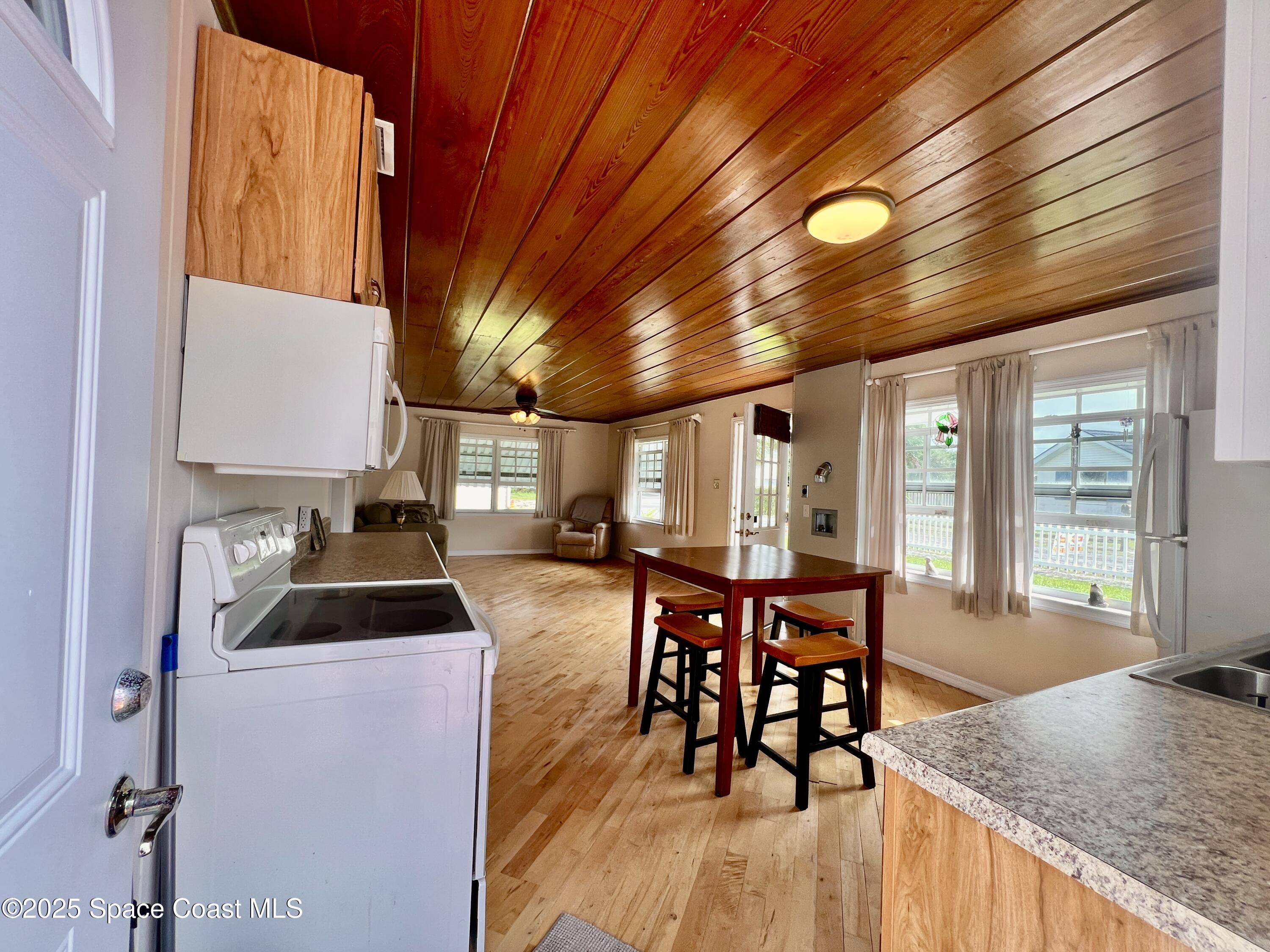 2767 Palm Drive Palm Bay, FL 32905 - Photo 7 of 26 a kitchen with stainless steel appliances granite countertop a stove a refrigerator a kitchen island a dining table and chairs with wooden floor