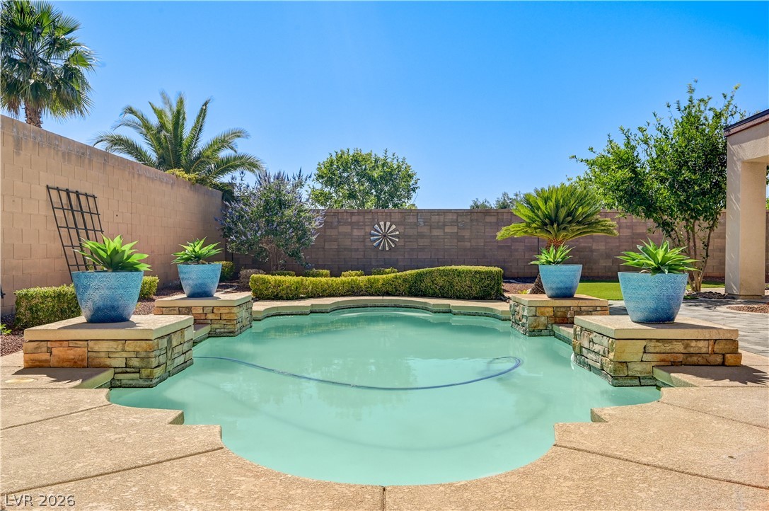 2793 Rosenhearty Drive Henderson, NV 89044 - Photo 59 of 77 A private backyard oasis features a custom-shaped swimming pool with decorative planters, perfect for warm weather enjoyment.