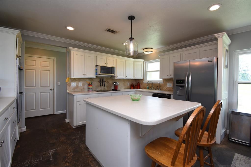 29400 Waller Gladish Road Waller, TX 77484 - Photo 12 of 39 a kitchen with kitchen island a refrigerator stove microwave and cabinets