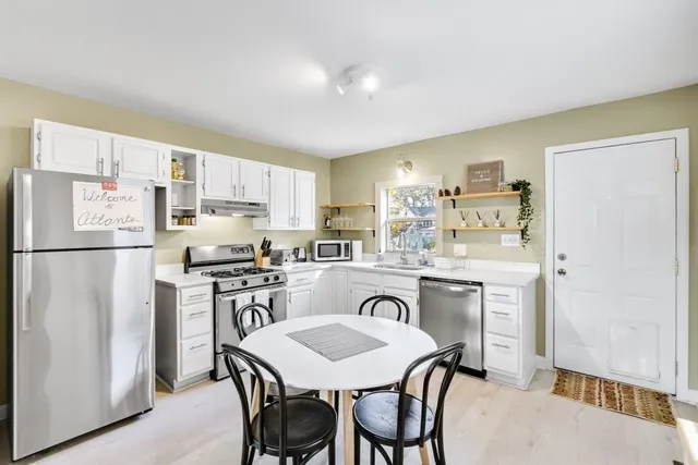 a kitchen with stainless steel appliances granite countertop a refrigerator a stove a sink a dining table and chairs