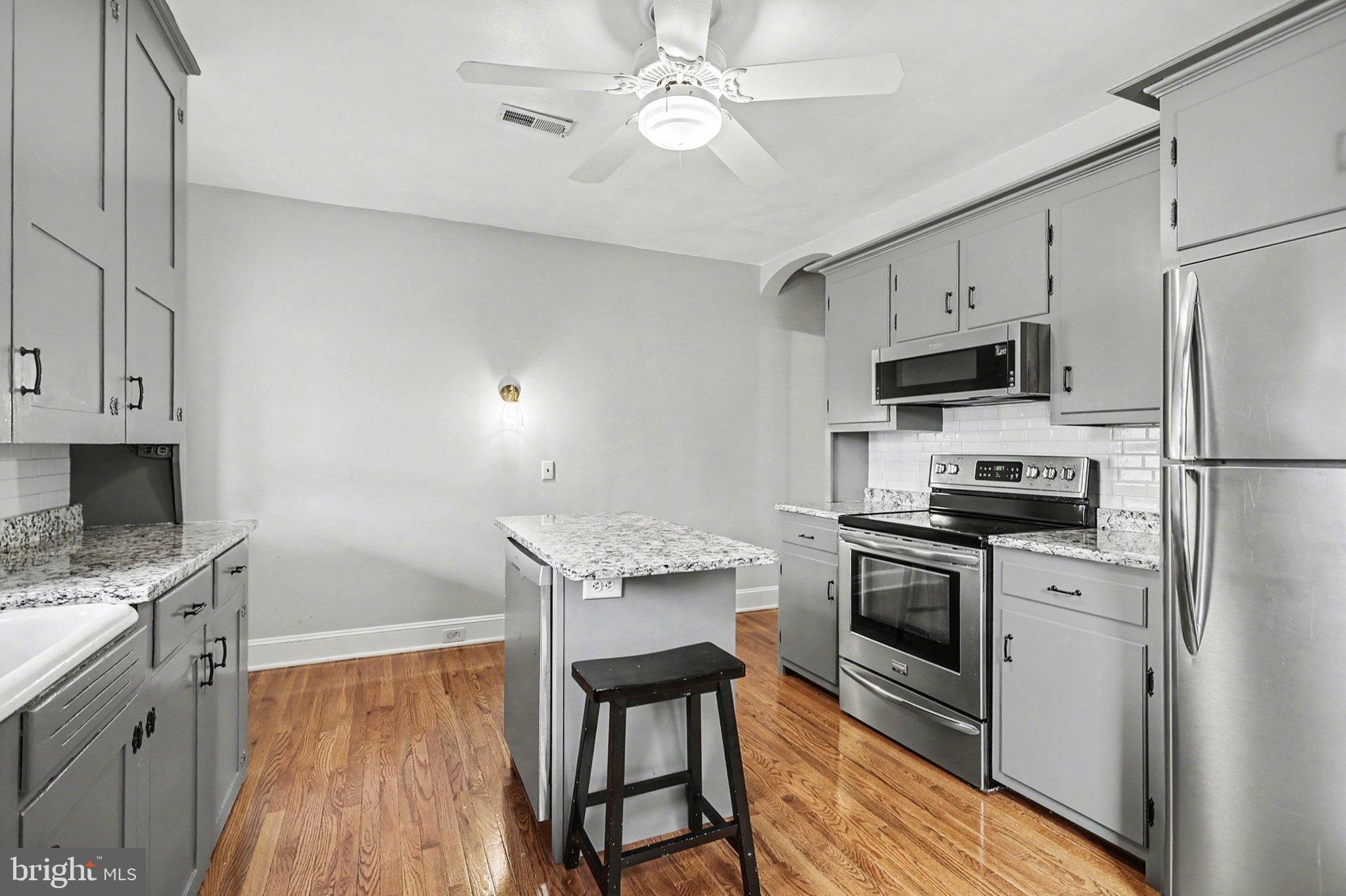 144 Seminary Avenue Gettysburg, PA 17325 - Photo 9 of 28 a kitchen with stainless steel appliances a stove a sink dishwasher a refrigerator white cabinets and wooden floor