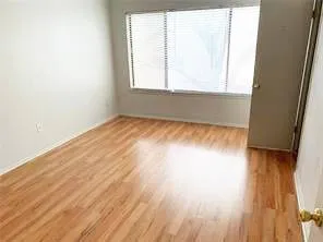 an empty room with wooden floor and a bathroom
