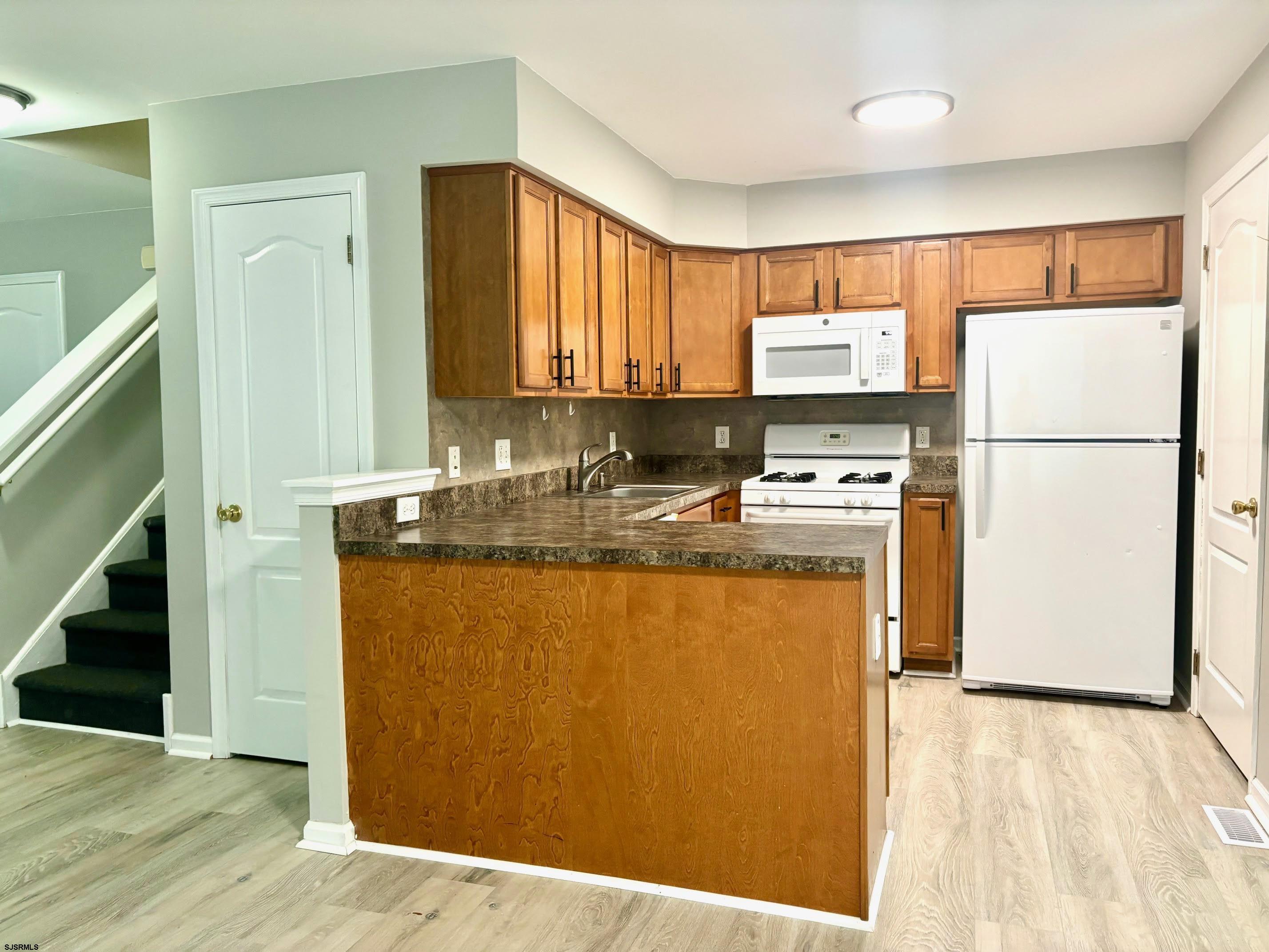 27 Oyster Bay, Unit G Absecon, NJ 08201 - Photo 11 of 31 a kitchen with stainless steel appliances granite countertop a refrigerator a stove a sink and a microwave