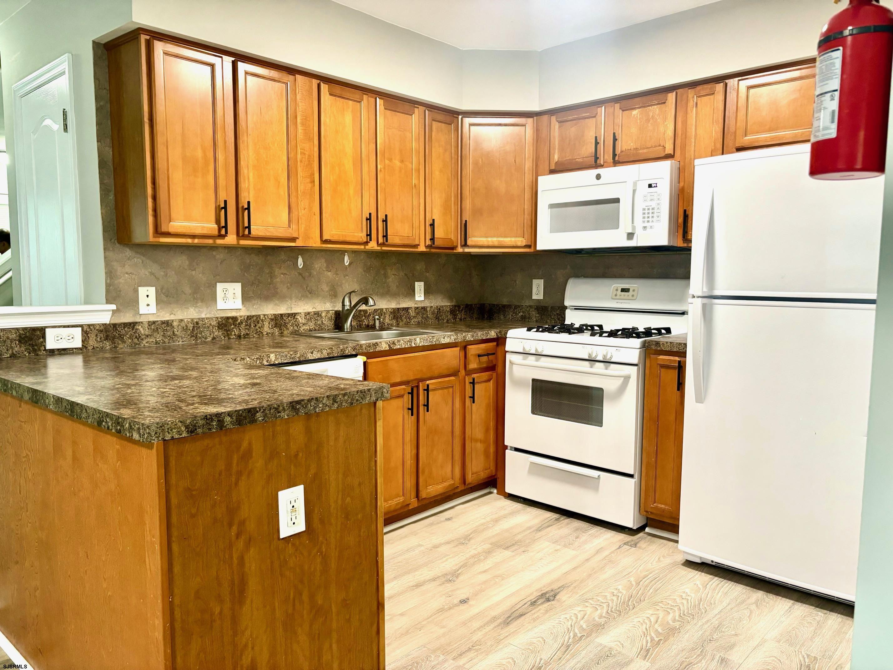 27 Oyster Bay, Unit G Absecon, NJ 08201 - Photo 12 of 31 a kitchen with a stove a sink and a refrigerator