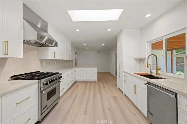 a kitchen with white cabinets and wooden floor
