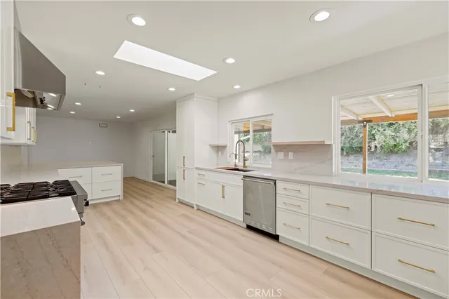 a kitchen with white cabinets and a window