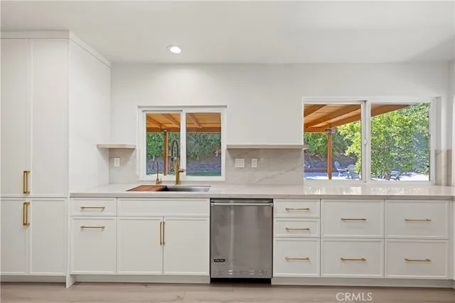 a kitchen with granite countertop white cabinets and stainless steel appliances