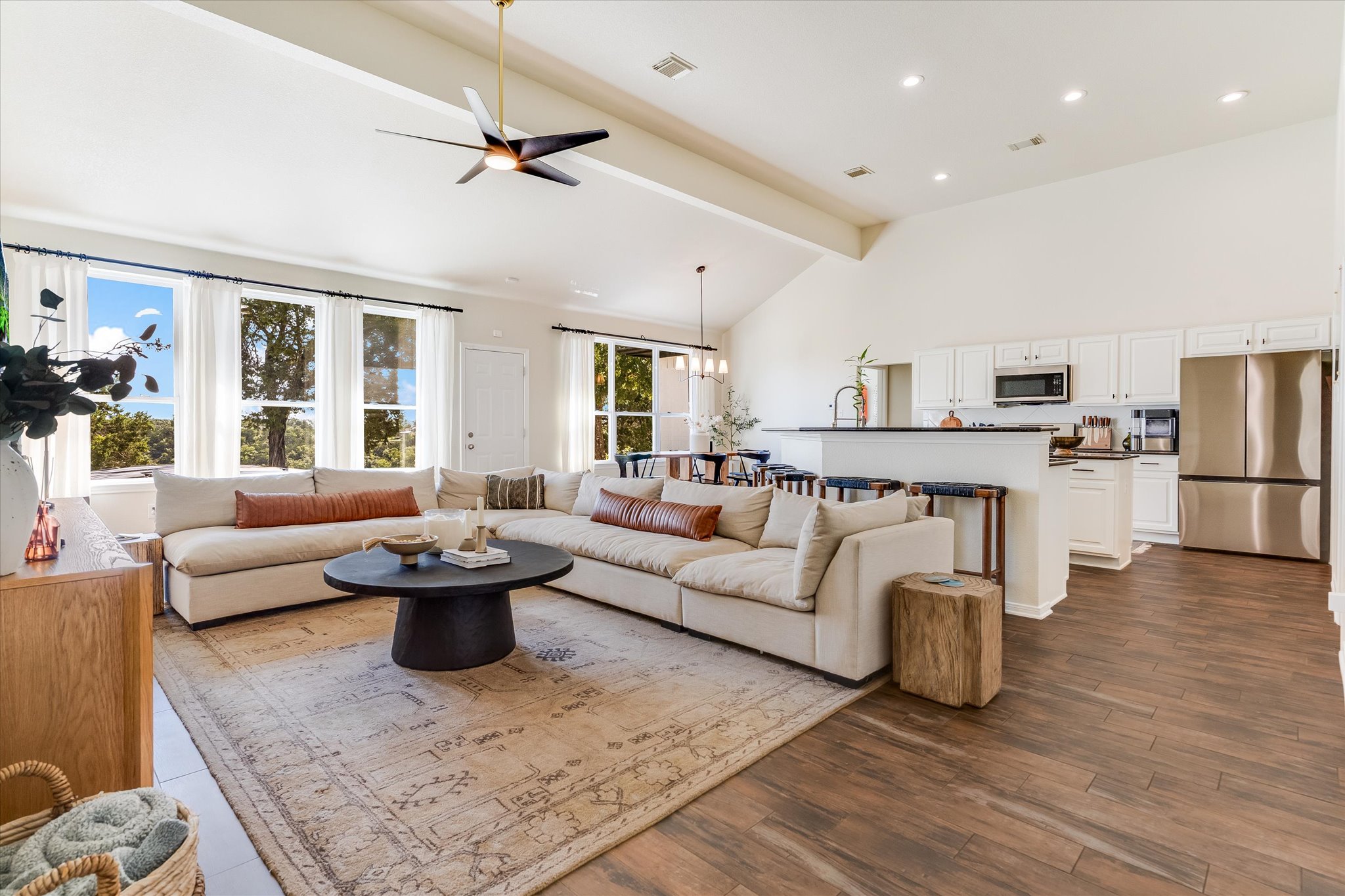 Living room with beam ceiling, high vaulted ceiling, dark tile/wood-type flooring, ceiling 
fan, and recessed lighting