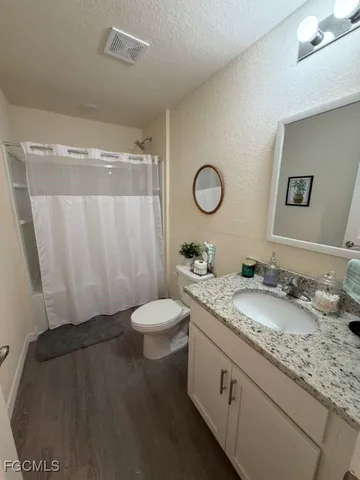 a bathroom with a granite countertop sink toilet and shower