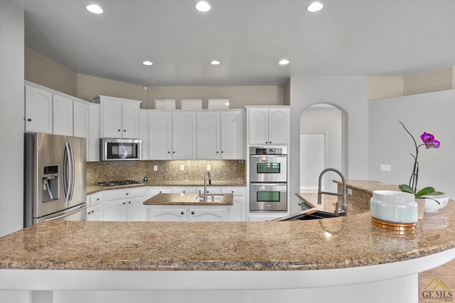 Undisclosed Address Bakersfield, CA 93311 - Photo 26 of 57 a kitchen with kitchen island granite countertop a sink stove and refrigerator