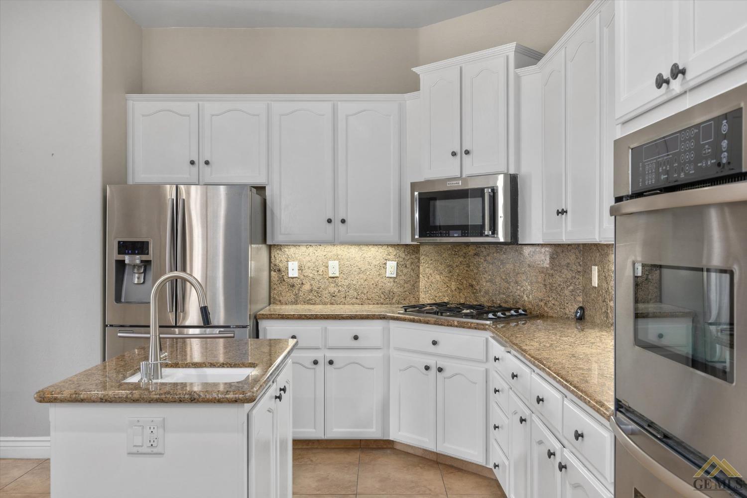 Undisclosed Address Bakersfield, CA 93311 - Photo 29 of 57 a kitchen with granite countertop white cabinets white stainless steel appliances and a sink