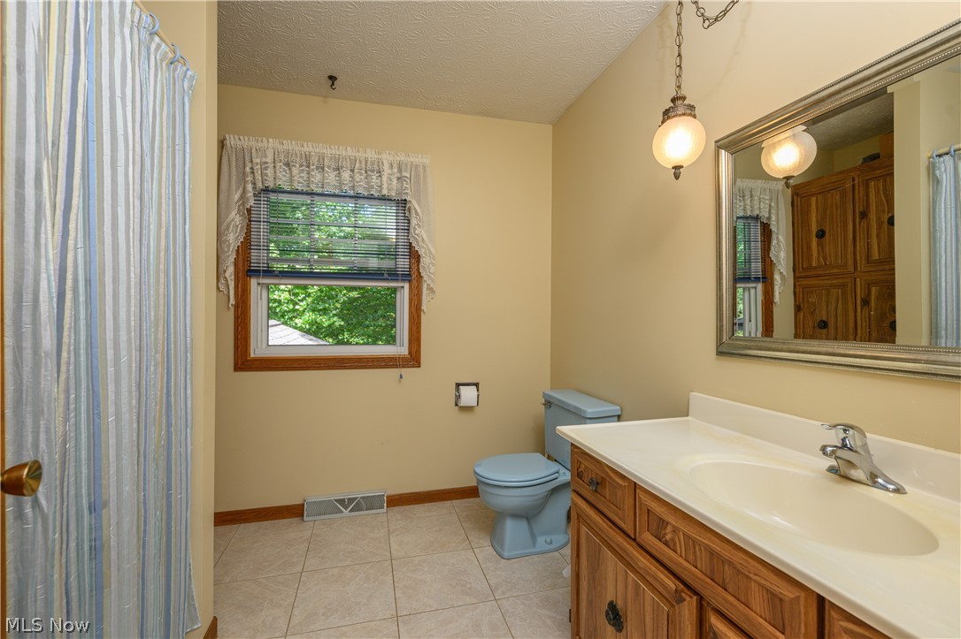 3281 Brenner Road Barberton, OH 44203 - Photo 23 of 33 Bathroom featuring tile patterned flooring, toilet, vanity, and a textured ceiling