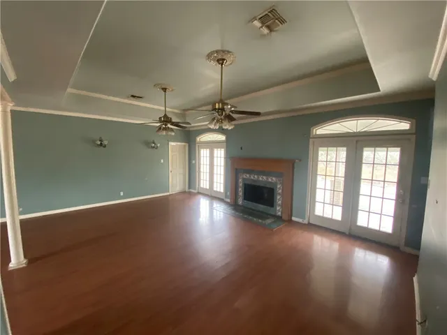 an empty room with wooden floor fireplace and windows