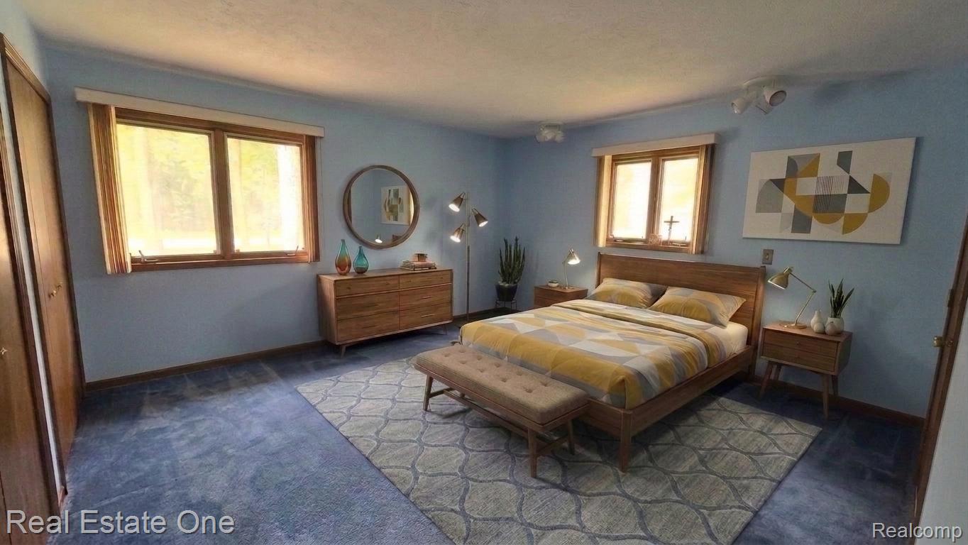 8950 Wise Road Commerce Township, MI 48382 - Photo 6 of 39 Bedroom featuring twin window units with wood frames, two built-in closet units with wood doors, blue wall paint, and blue carpeting