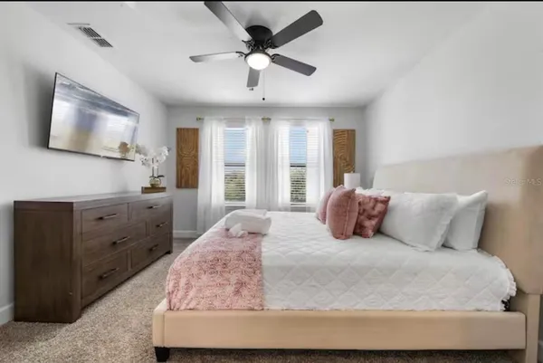 a bedroom with a large bed and a flat tv screen on dresser