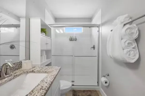 a bathroom with a granite countertop sink a toilet and shower