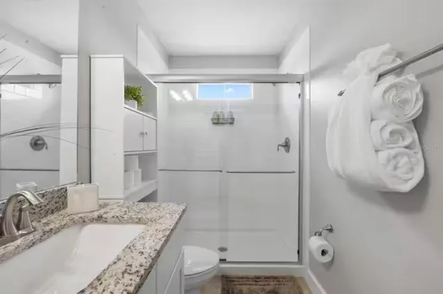 a bathroom with a granite countertop sink a toilet and shower