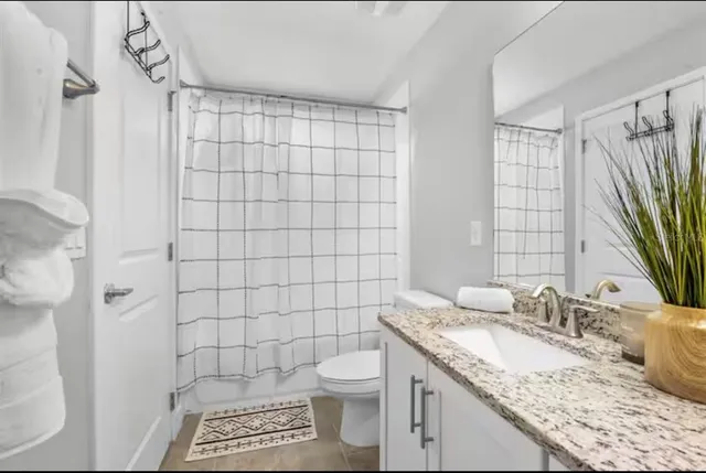 a bathroom with a granite countertop sink a toilet and a shower