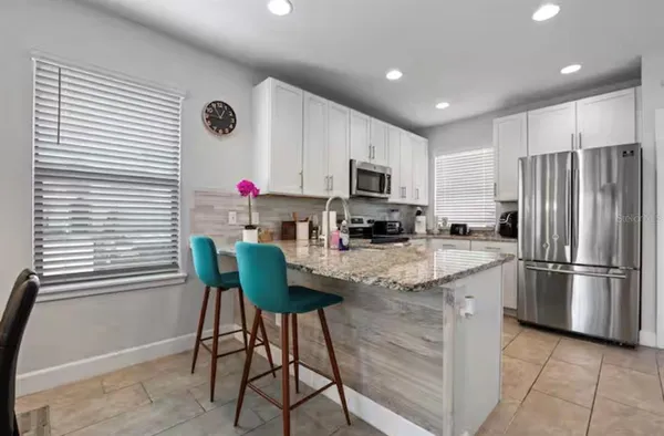 a kitchen with kitchen island stainless steel appliances a stove a sink a refrigerator cabinets and a dining table