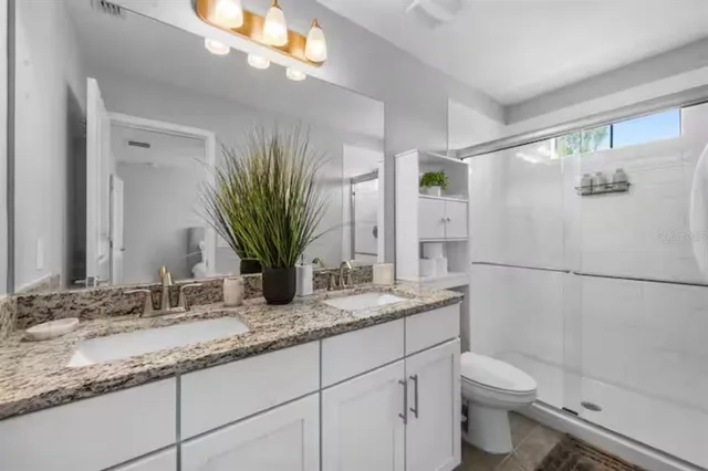 a bathroom with a granite countertop sink a toilet and a mirror