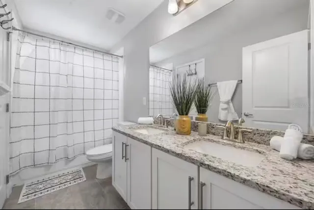 a bathroom with a granite countertop sink a toilet and a mirror