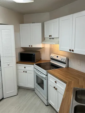 a kitchen with white cabinets and white appliances