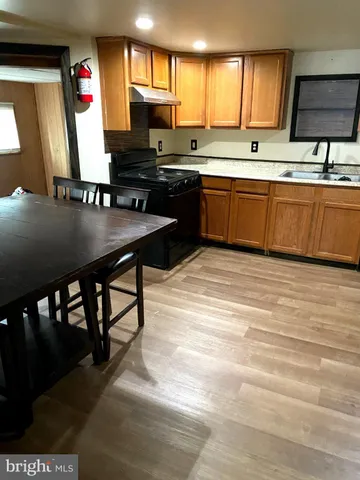 a kitchen with stainless steel appliances granite countertop a table chairs sink and cabinets