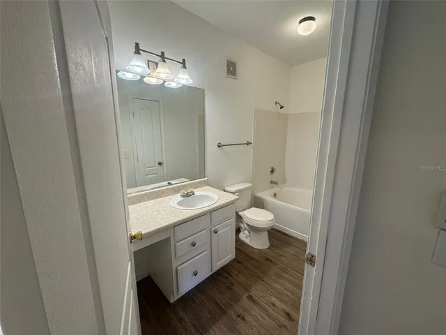 a spacious bathroom with a double vanity sink toilet mirror and bathtub