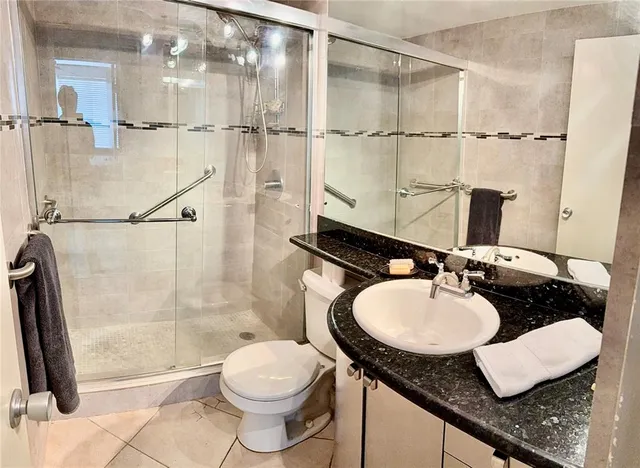 a bathroom with a granite countertop sink a mirror and a shower